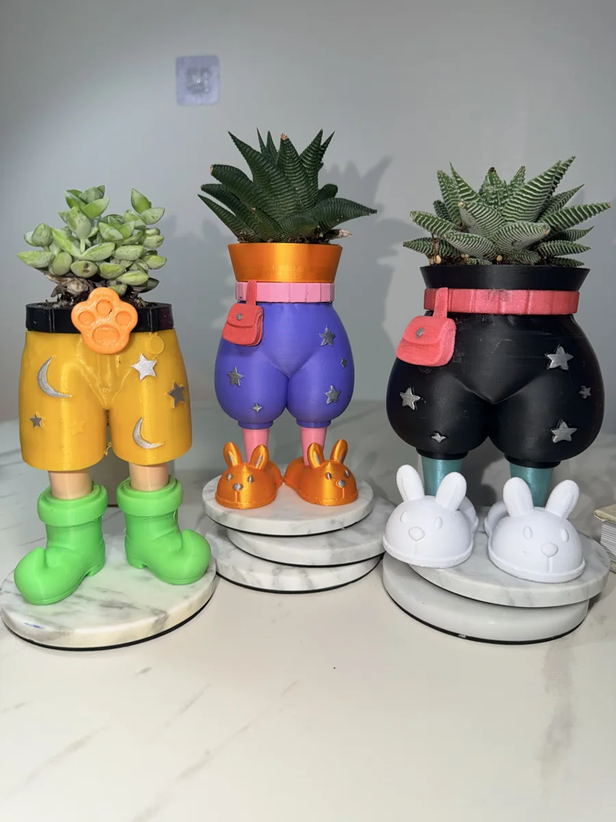 Yellow shorts planter beside purple and black pants planters with succulents